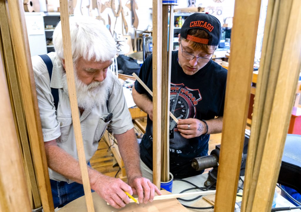 Paul Williams (left) helps Scott Beatty build his ‘backpack’ guitar. It has a smaller body, meant to easily fit in a pack. Beatty is in the Culture of Recovery program which teaches instrument making to people recovering from addiction. Paul Williams (left) helps Scott Beatty build his 'backpack' guitar. It has a smaller body, meant to easily fit in a pack. Beatty is in the Culture of Recovery program which teaches instrument making to people recovering from addiction. (Caitlin Tan/West Virginia Public Broadcasting)