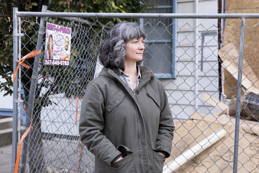 2019 11 05-r wisniewski-Sara Gallo-fishtown-house damage_06 Sara Gallo stands between her home and the new construction next door on November 5, 2019. Due to the demolition and rebuilding of the twin house adjoining hers, her home now suffers structural issues, settling, and leaking. (Rachel Wisniewski for WHYY)