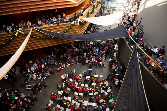 Jay Krush leads the audience in a jingling of keys, while an ensemble of tubas performs 