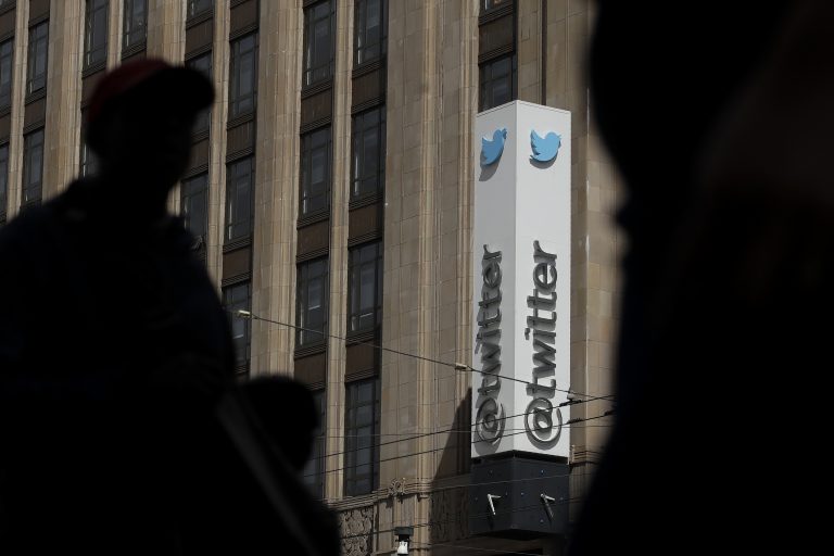 Pedestrians walking across the street from the Twitter office building in San Francisco. (Jeff Chiu/AP Photo)