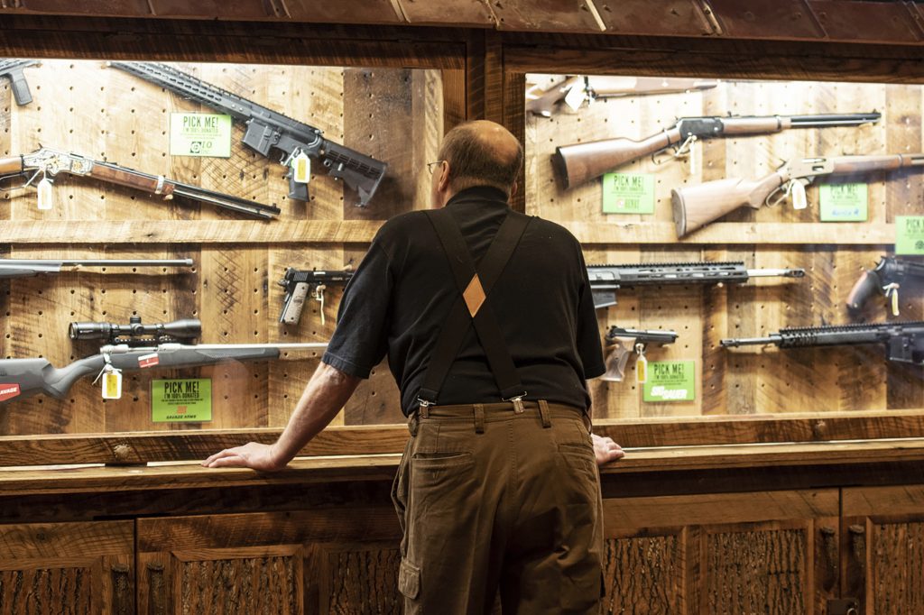 In this April 25, 2019, file photo, a man looks at cases of firearms in the halls of the Indianapolis Convention Center where the National Rifle Association will be holding its 148th annual meeting in Indianapolis. The number of background checks conducted by federal authorities is on pace to break a record by the end of this year. (Lisa Marie Pane/AP Photo)
