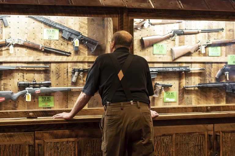 In this April 25, 2019, file photo, a man looks at cases of firearms in the halls of the Indianapolis Convention Center where the National Rifle Association will be holding its 148th annual meeting in Indianapolis. The number of background checks conducted by federal authorities is on pace to break a record by the end of this year. (Lisa Marie Pane/AP Photo)