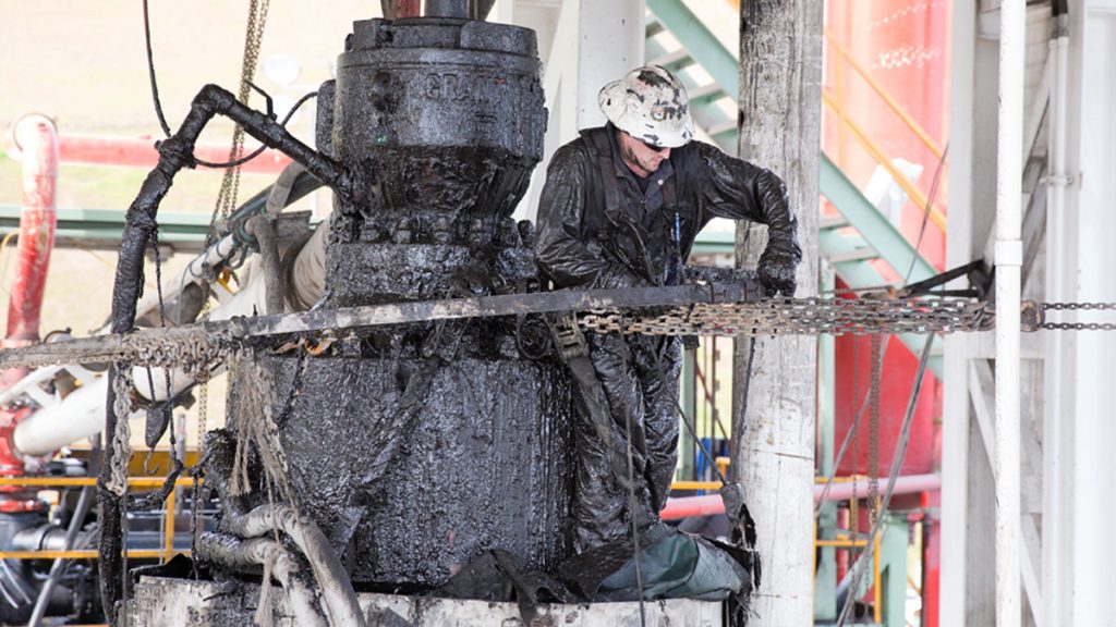 cabot_drill_site_1200-1 A drill worker covered in mud, shale, and drill cuttings seals off a well and cleans the blowout preventer at a Cabot Oil and Gas natural gas drill site in Kingsley, Pa. (Lindsay Lazarski/WHYY)