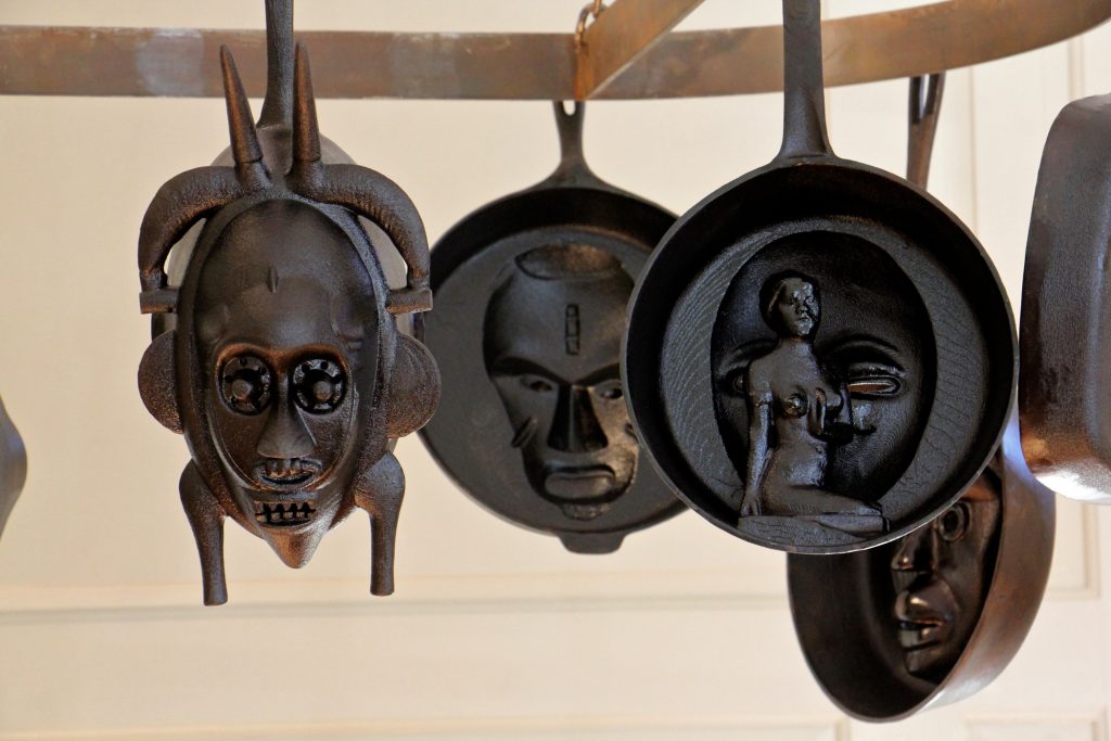 2019 01 17-e lee-princeton bainbridge house-hugh hayden exhibit skillets Cast iron skillets hanging in the kitchen at Bainbridge House are from Hugh Hayden's series, 'American Food.' They are modeled from African Masks and historical artifacts in the Princeton University Art Museum collections. (Emma Lee/WHYY)