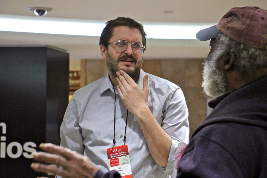 2020 01 10-e lee-ian olasov-philadelphia suburban station-popup philosophy booth Ian Olasov (left), a part-time philosophy professor at Brooklyn College, engages with passersby at the Ask a Philosopher pop-up booth at Suburban Station in Center City. (Emma Lee/WHYY)