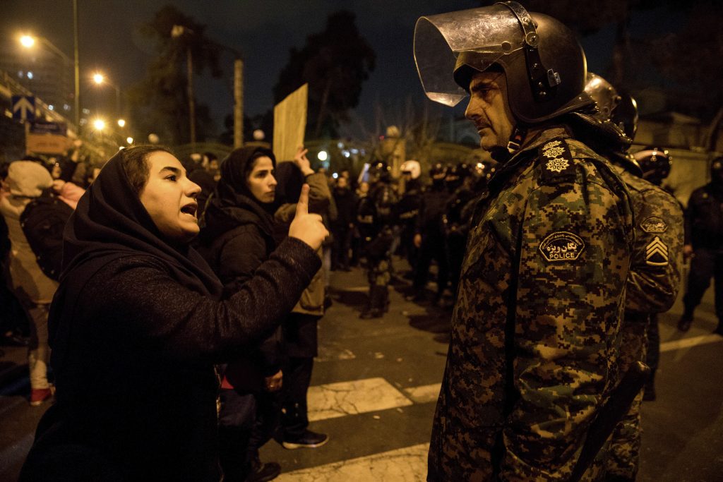 ADDITION Iran Plane Crash A woman attending a candlelight vigil to remember the victims of the Ukraine plane crash, talks to a policeman, at the gate of Amri Kabir University in Tehran, Iran. (Mona Hoobehfekr/ISNA via AP)
