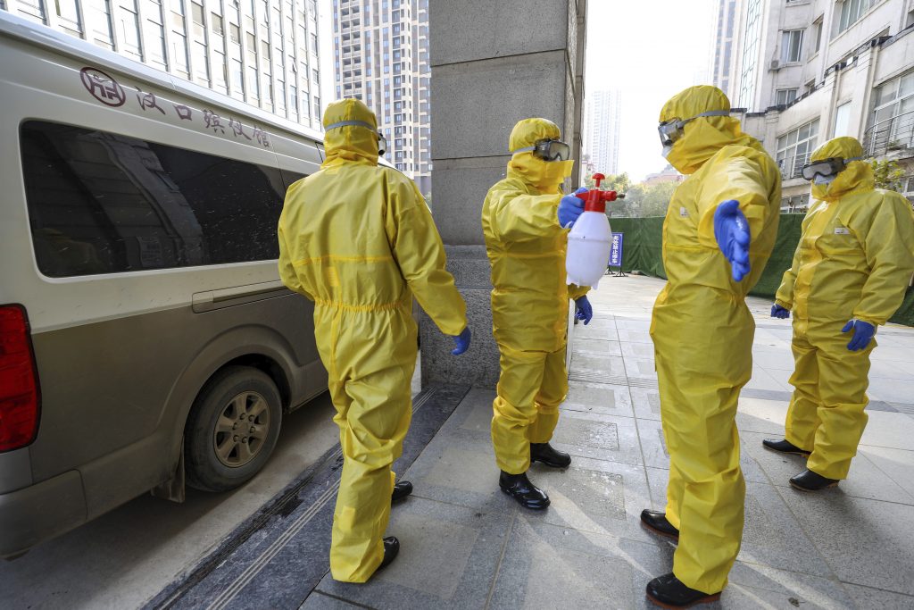 China Outbreak Funeral workers disinfect themselves after handling a virus victim in Wuhan in central China's Hubei Province, Thursday, Jan. 30, 2020. China counted 170 deaths from a new virus Thursday and more countries reported infections, including some spread locally, as foreign evacuees from China's worst-hit region returned home to medical observation and even isolation. (Chinatopix via AP)