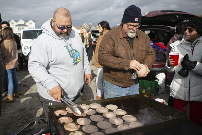 Todd Arsenault, right, and Scott Gallagher cook during the 2020 polar bear plunge in Margate, NJ on Wednesday, January 1, 2020. (Miguel Martinez for WHYY)