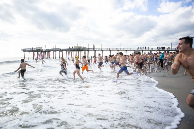 Participants of the 2020 polar bear plunge in Margate, NJ  run to the ocean on Wednesday, January 1, 2020. (Miguel Martinez for WHYY)