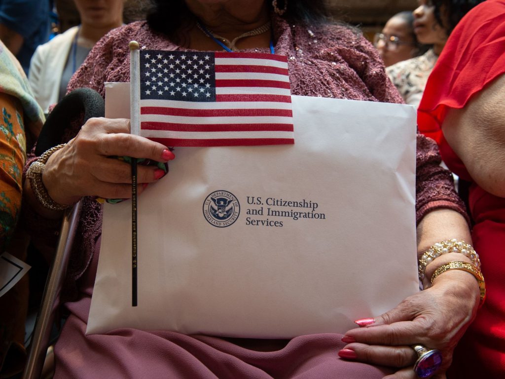 A newly sworn-in U.S. citizen holds the U.S. flag and paperwork during a 2018 naturalization ceremony in New York City. The Department of Homeland Security has agreed to share its records with the U.S. Census Bureau to help produce data about the U.S. citizenship status of every person living in the country, as ordered by President Trump. A newly sworn-in U.S. citizen holds the U.S. flag and paperwork during a 2018 naturalization ceremony in New York City. (Bryan R. Smith/AFP via Getty Images)