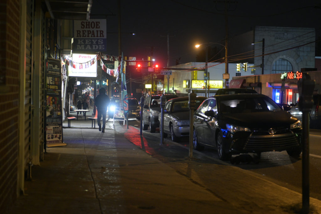 Led Lights in Olney A street is shown at nighttime, with a few passersby walking by.