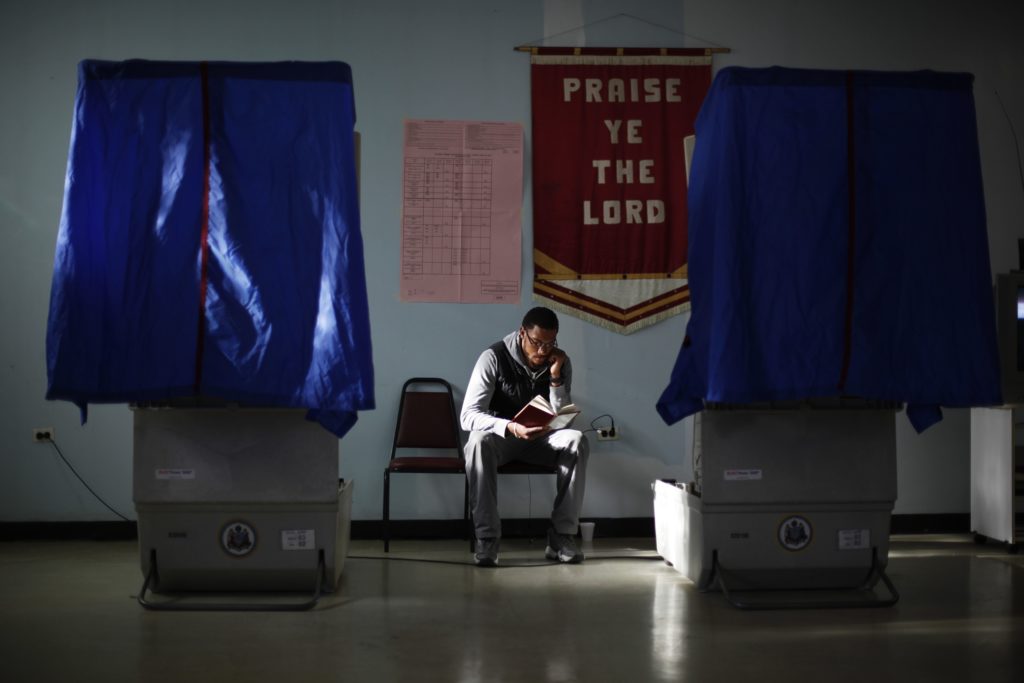 APTOPIX Pennsylvania Primary Election worker Khalid Battle reads a book as he waits for voters to cast their ballots in Pennsylvania primary election at Memorial Gospel Crusades Church in Philadelphia. (AP Photo/Matt Rourke)