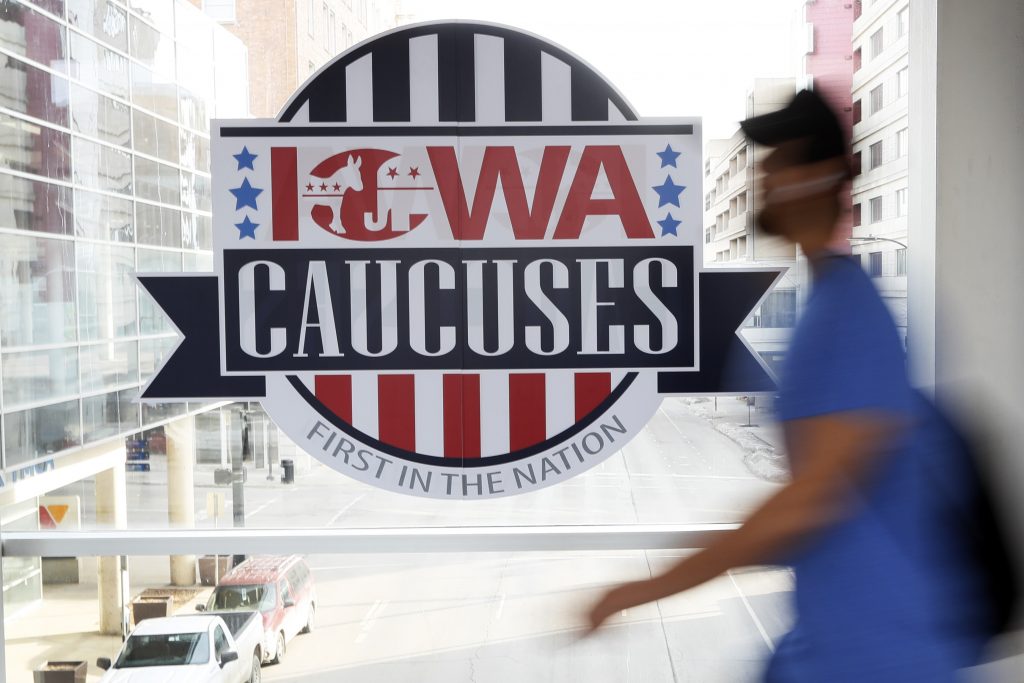 Election 2020 Iowa Caucus A pedestrian walks past a sign for the Iowa Caucuses on a downtown skywalk, Tuesday, Feb. 4, 2020, in Des Moines, Iowa. (Charlie Neibergall/AP Photo)