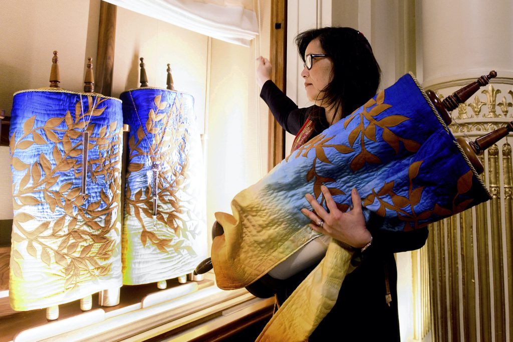 Jacqueline Mates-Muchin In this Saturday, Feb. 1, 2020, photo, Rabbi Jacqueline Mates-Muchin removes a Torah scroll from the ark, a cabinet that houses scrolls of the Hebrew Bible, while preparing for Shabbat morning service at Temple Sinai in Oakland, Calif. (Noah Berger/AP Photo)