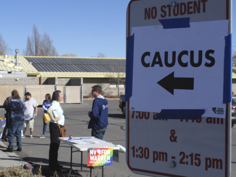 Volunteers for various campaigns talk to voters as they enter a presidential caucus site at Mendive Middle School in Sparks, Nevada on Saturday, Feb. 22, 2020. (Scott Sonner/AP Photo)