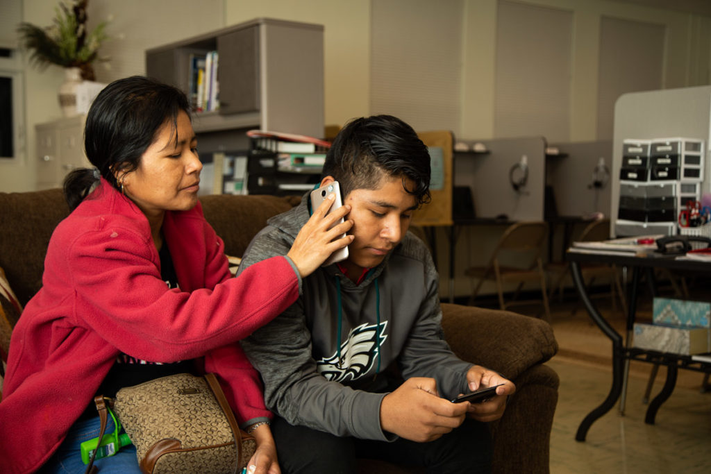 Chambersburg_256 Fredy Garcia Morales and his mom Margarita talk to his sisters on the phone while sitting in the King Street Ministry Center in Chambersburg, Pa. (Jeffrey Stockbridge for Keystone Crossroads)