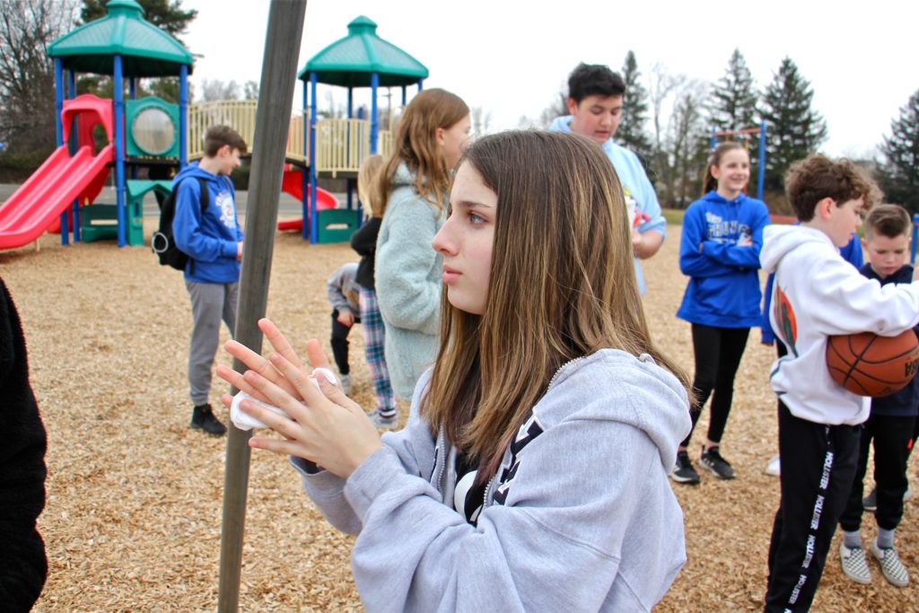 2020 03 06-e lee-warrington titus elementary school-virus shuts down schools Tamanend Middle School student Brianna Muntz, 14, uses a disposable hand wipe as she plays with friends on the Titus Elementary School playground. Both schools were closed, along with three others in Central Bucks County, as a precaution against the spread of COVID-19. (Emma Lee/WHYY)