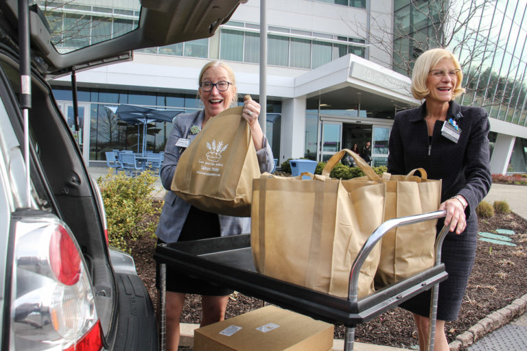 At Einstein Medical Center Montgomery, Chief Nursing Officer Annmarie Papa (left) and Chief Operating Officer Beth Duffy accept a donation of bagels and croissants from Four Worlds Bakery. (Emma Lee/WHYY)