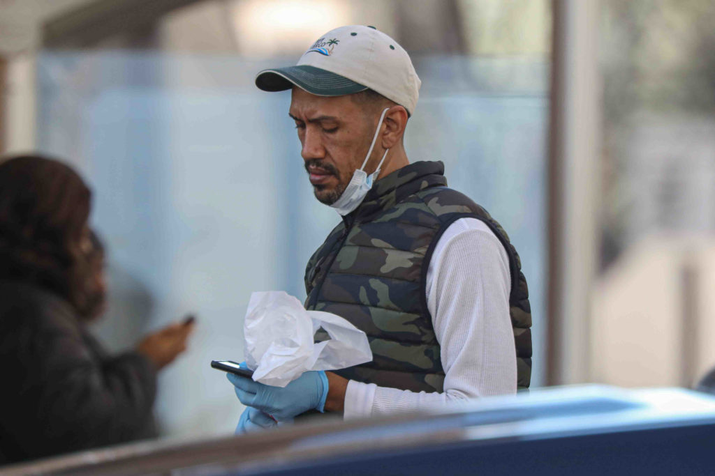 A man walks on Market Street in Wilmington, Del., wearing a protective mask and gloves.