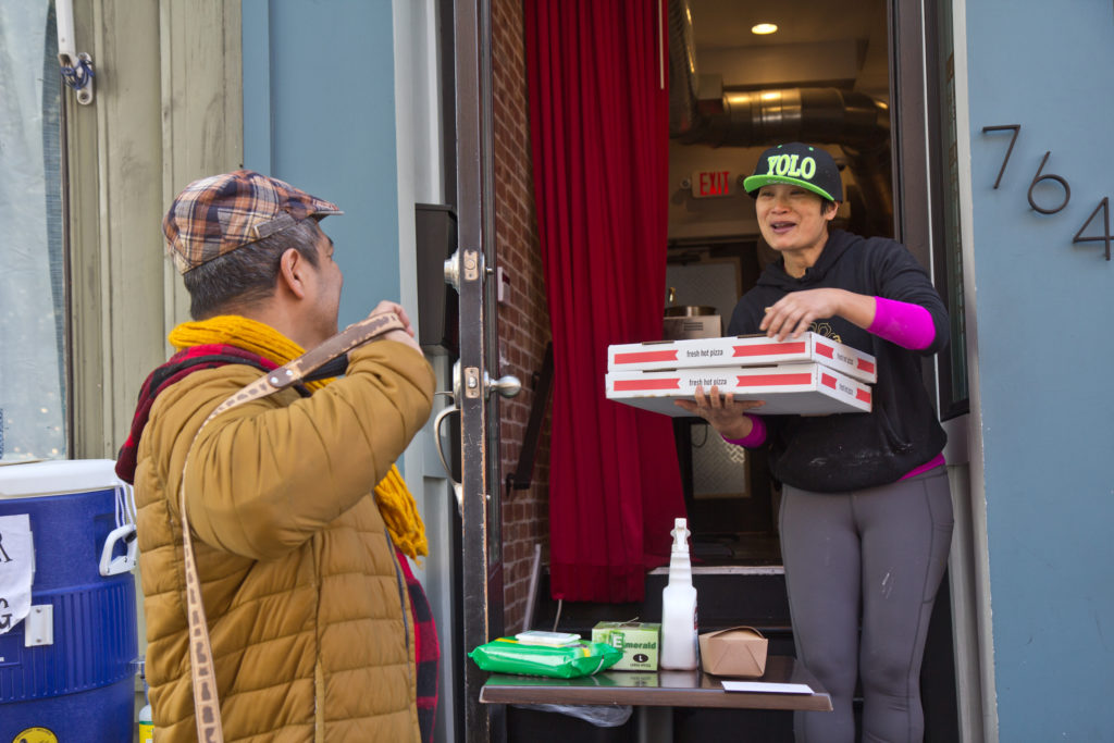 2020 3 18 k paynter kalaya food giveaway-9 Kalaya owner Nok Suntaranon (right) hands out donated pizza to community members in need. (Kimberly Paynter/WHYY)