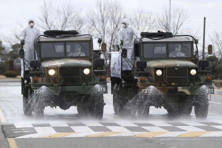 South Korean army trucks spray disinfectant as a precaution against the coronavirus on a street in Ulsan, South Korea, Tuesday, March 3, 2020. China's coronavirus caseload continued to wane Tuesday even as the epidemic took a firmer hold beyond Asia, with three countries now exceeding 1,000 cases and the U.S. reporting its sixth death. (Kim Young-tae/Yonhap via AP)