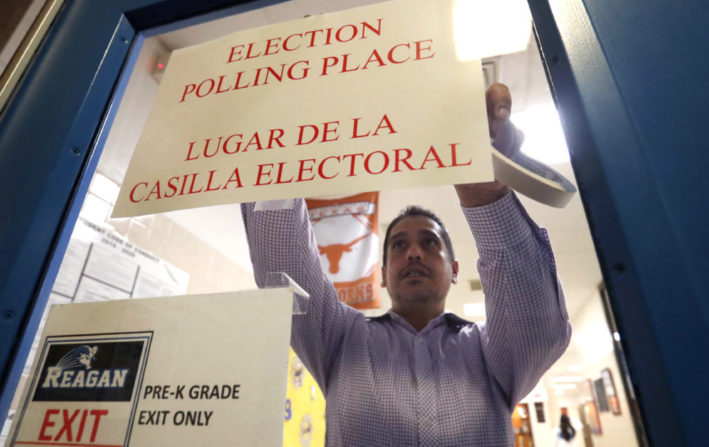 CORRECTION Elections 2020 Texas Dallas County election worker Maxx Nunez tapes up a sign before polls open for Super Tuesday voting at John H. Reagan Elementary School in the Oak Cliff section of Dallas, Tuesday, March 3, 2020. (AP Photo/LM Otero)