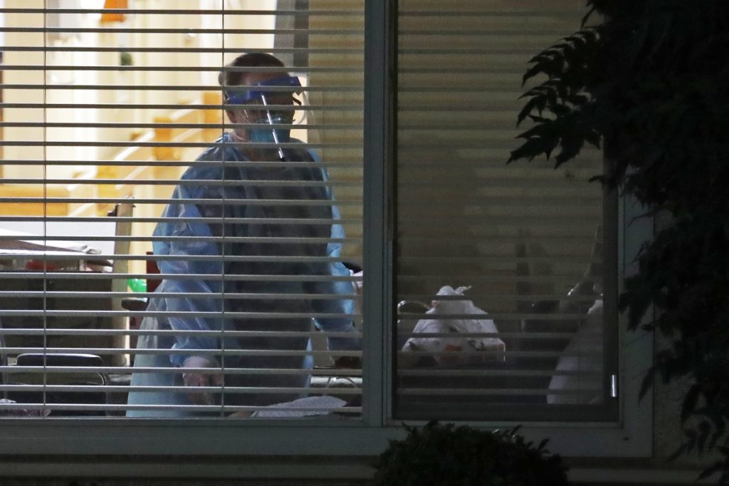 Virus Outbreak US A worker wearing protective gear is seen through a window as she works in the room of Susan Hailey, 76, who has tested positive for the new coronavirus, Tuesday, March 10, 2020, at the Life Care Center in Kirkland, Wash., near Seattle. (AP Photo/Ted S. Warren)