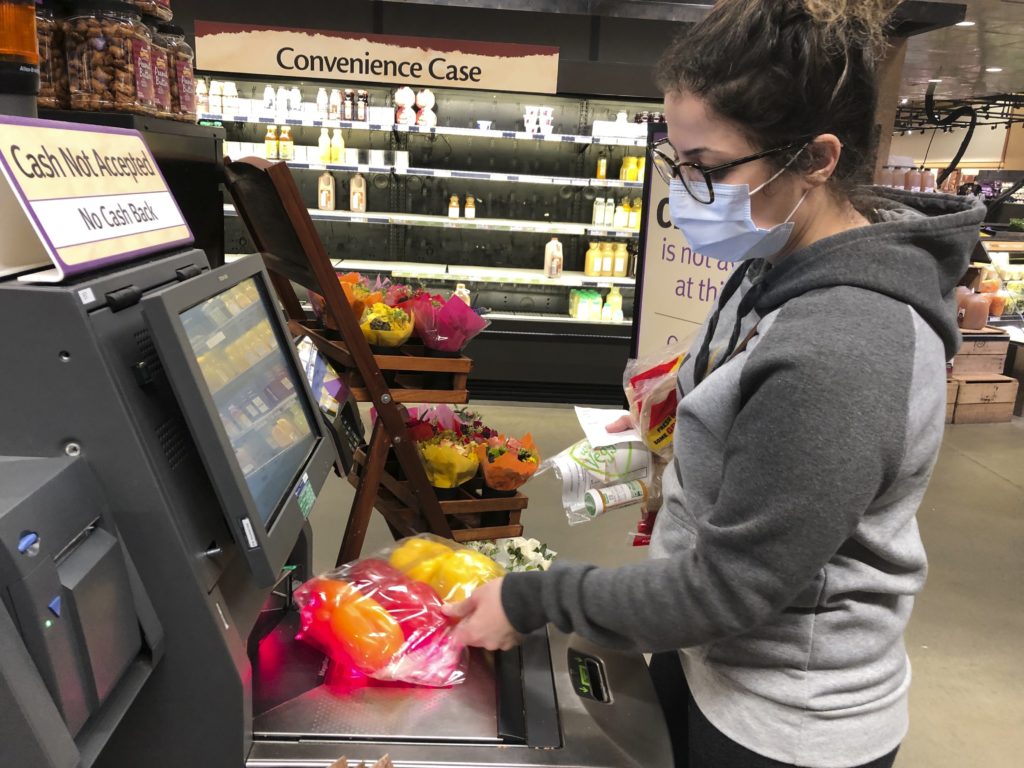 Virus Outbreak County Shutdown Wearing a surgical mask, Melissa Hall checks out of a Wegmans supermarket, Friday, March 13, 2020 in King of Prussia, Pa. (Michael Rubinkam/AP Photo)