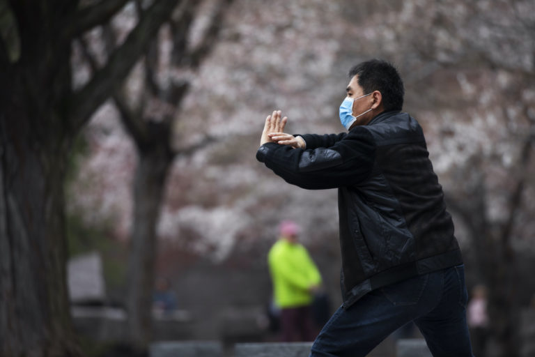 Zhili Sun, practices tai chi by blooming cherry trees while wearing a mask  along the tidal basin in Washington. (Jacquelyn Martin/AP Photo)