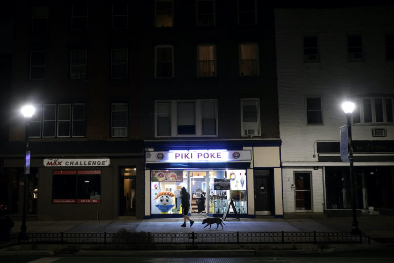 A man walks his dog on a mostly empty street before the start of a 10 p.m. curfew in Hoboken, N.J., Tuesday, March 17, 2020. (Seth Wenig/AP Photo)