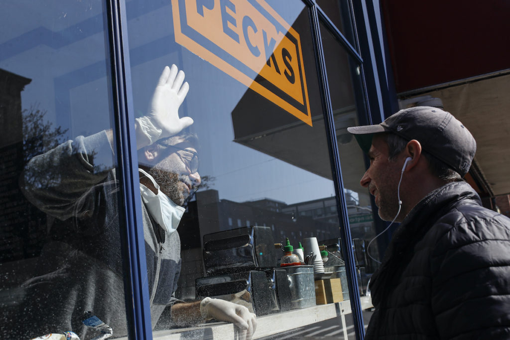 Theodore Peck Peck's Food owner Theodore Peck touches hands with a customer through window glass while closing his storefront due to the coronavirus outbreak, Wednesday, March 18, 2020, (AP Photo/John Minchillo)