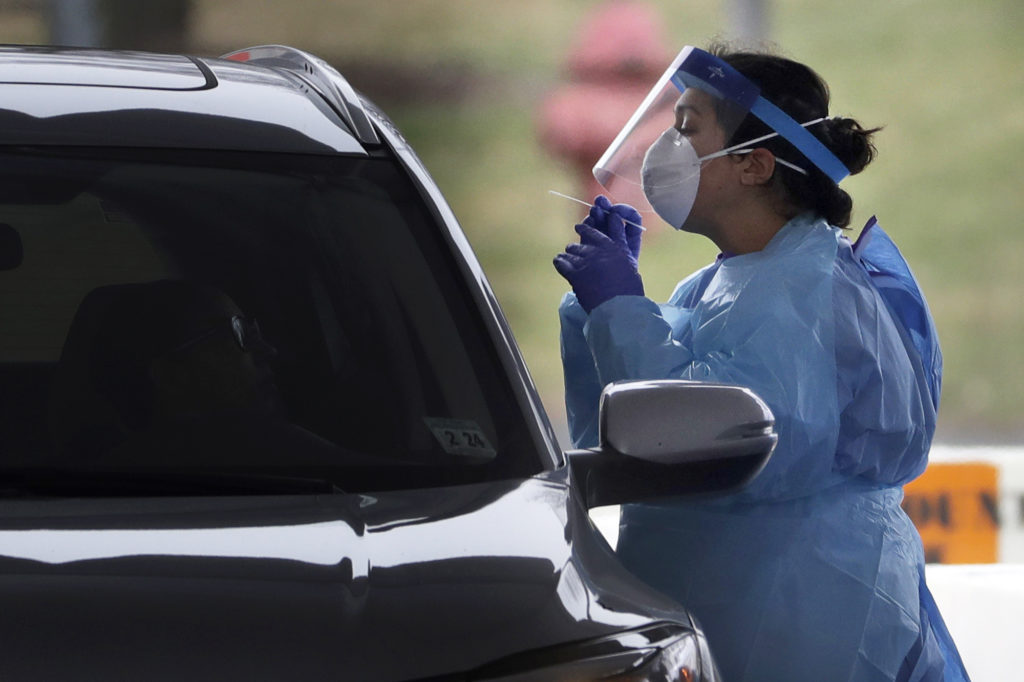 Virus Outbreak New Jersey A medical staff member in protective gear administers a test for COVID-19 at a drive-through testing center in Paramus, N.J., Friday, March 20, 2020. (Seth Wenig/AP Photo)
