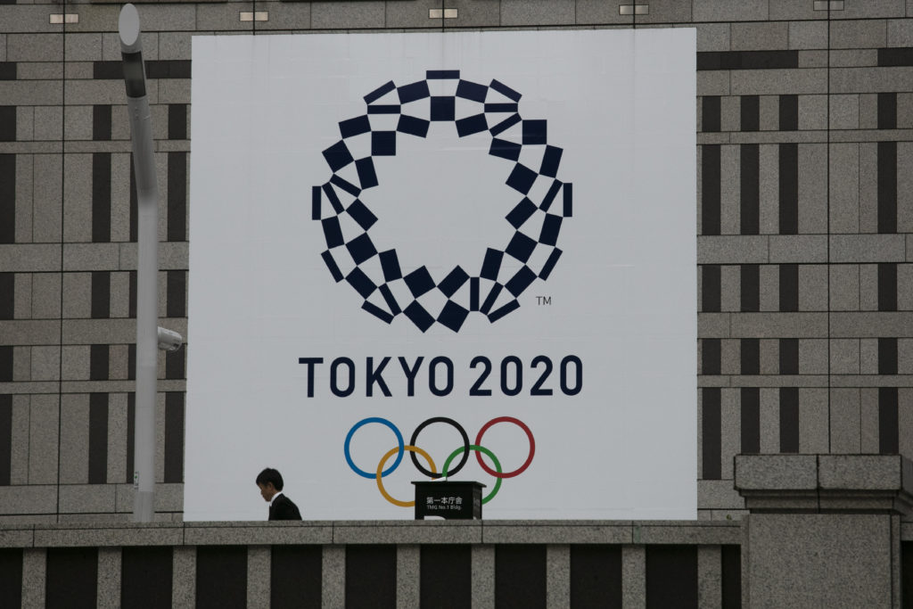 Virus Outbreak Olympics Tokyo 2020 A man walks past a large banner promoting the Tokyo 2020 Olympics in Tokyo, Monday, March 23, 2020. The IOC will take up to four weeks to consider postponing the Tokyo Olympics amid mounting criticism of its handling of the coronavirus crisis that now includes Canada saying it won't send a team to the games this year and the leader of track and field, the biggest sport at the games, also calling for a delay. (AP Photo/Jae C. Hong)