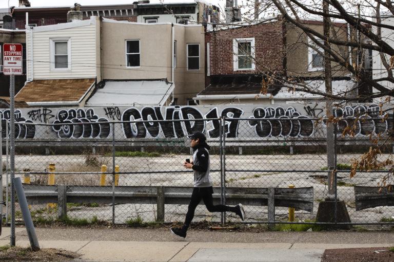A jogger runs past a wall painted with the word 