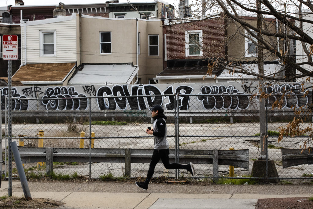 Virus Outbreak Pennsylvania A jogger runs past a wall painted with the word