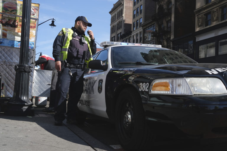 A Newark police officer uses his car megaphone to encourage social distancing at an intersection in Newark, N.J., Thursday, March 26, 2020. (AP Photo/Seth Wenig)