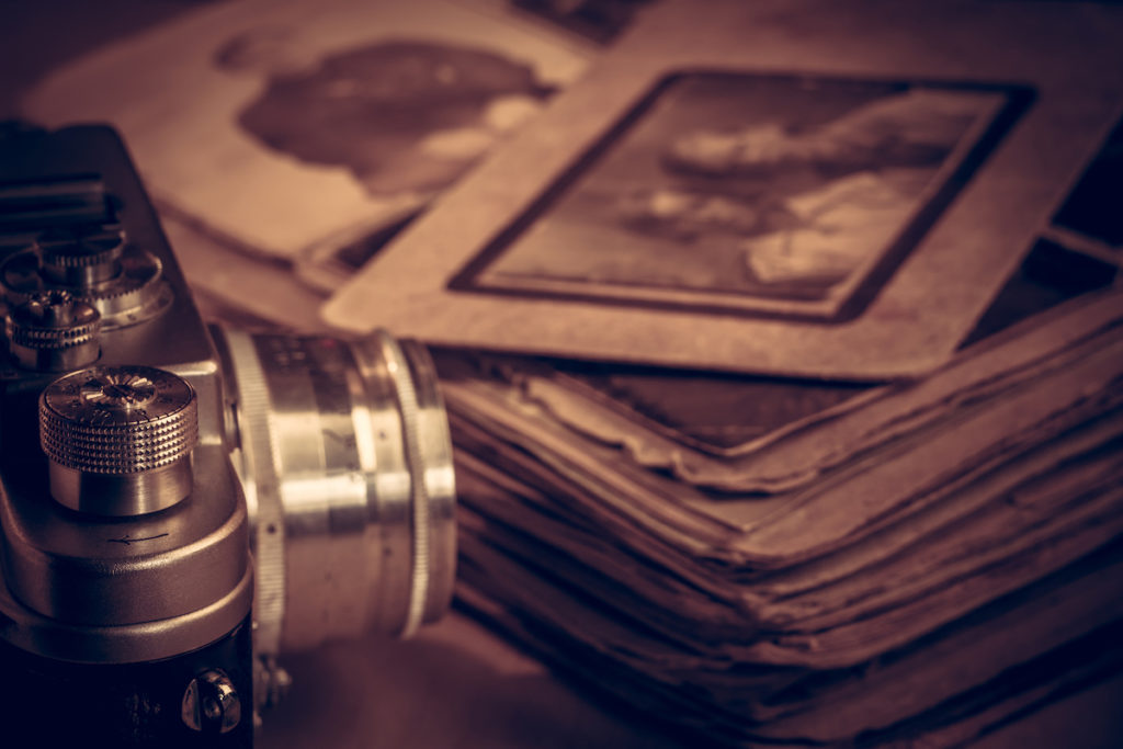 A Camera Next To An Old Photo Album On The Table. A camera next to an old photo album on the table.