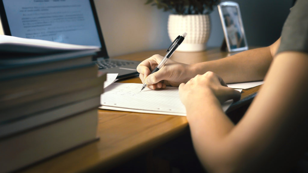 College Or University Student Doing School Homework At Home. Working Late At Night. Young Woman Writ (TeroVesalainen/BigStock)