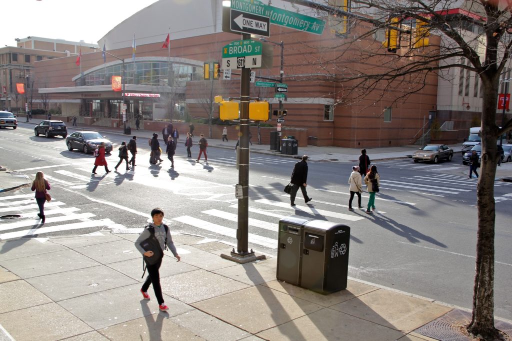 Students cross the street at Temple. Temple, Penn and other regional schools are closing campuses because of coronavirus concerns, making business unpredictable for restaurants near college campuses. (Emma Lee/WHYY)