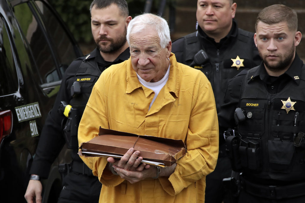 Jerry Sandusky Former Penn State football head coach Jerry Sandusky is led by authorities while in an orange jumpsuit