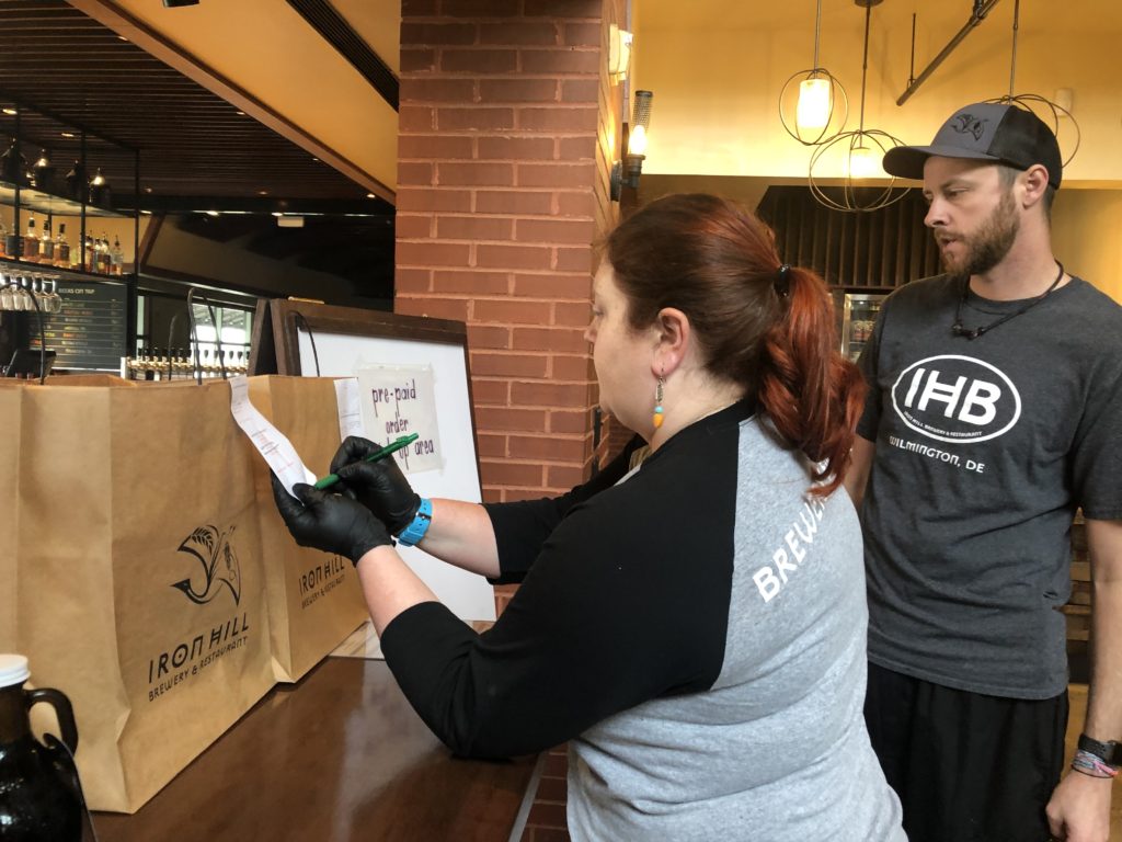 takeout Moriah Guise and Dustin Mitchell check orders at Iron Hill Brewery. (Cris Barrish/WHYY)