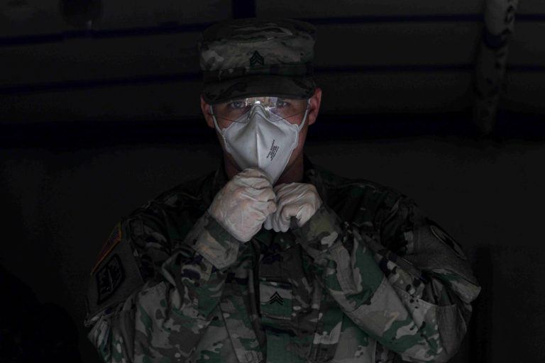Delaware National Guard Sergeant Whitlock readies himself to deliver packaged food from a medium tactical vehicle on Wednesday, April 8, 2020, at Frederick Lodge Manufactured Home Community in Townsend, Del. (Saquan Stimpson for WHYY)