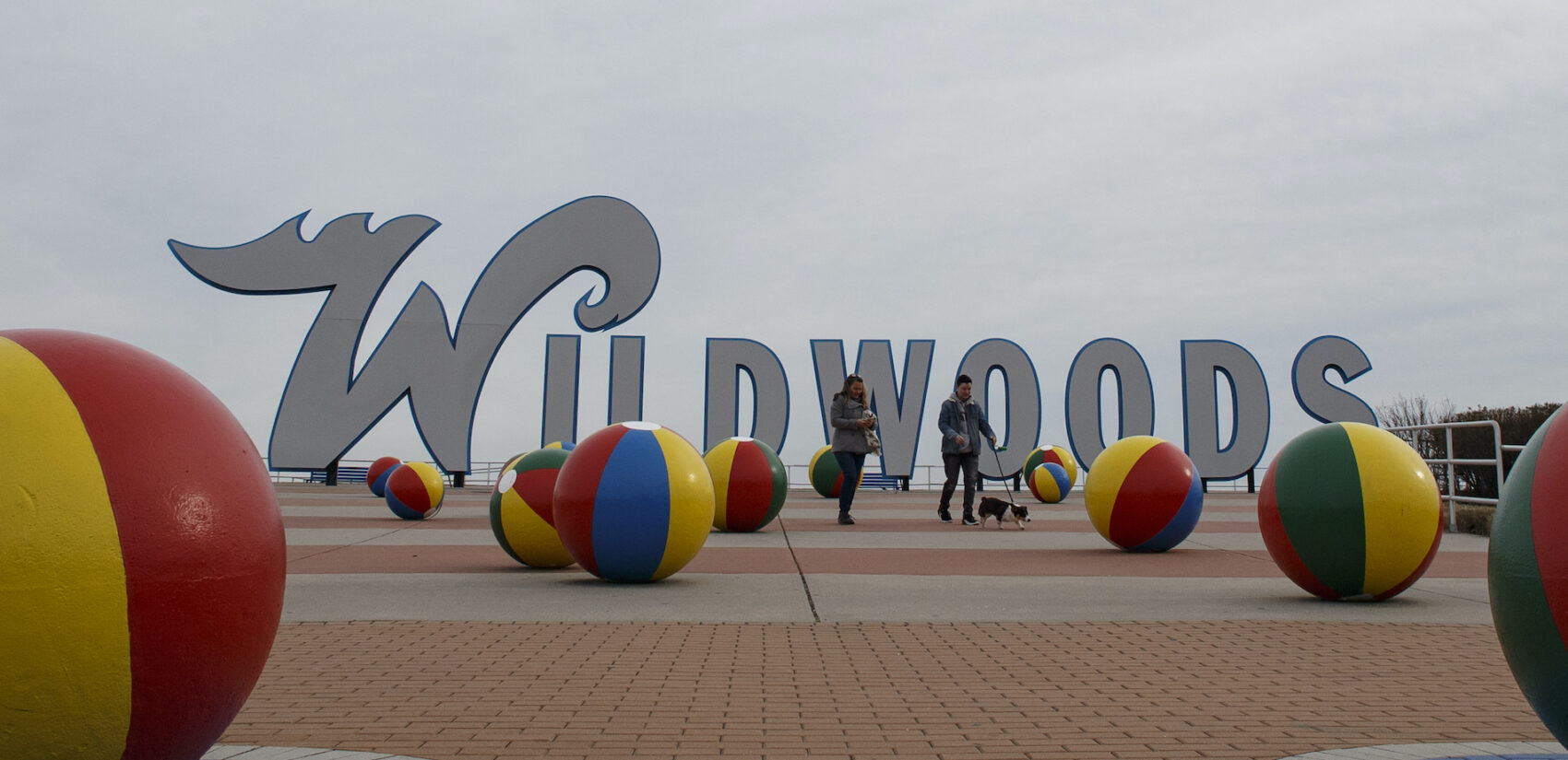 People walk a dog along the boardwalk in Wildwood