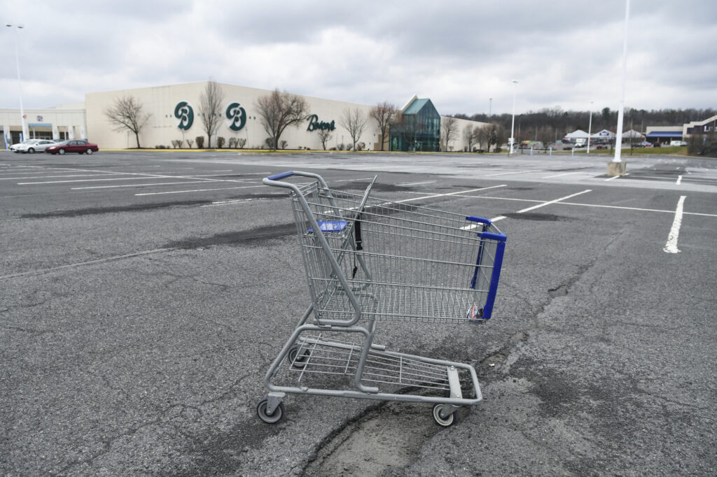 In this Tuesday, March 17, 2020, photo, a lone shopping cart sits in an empty parking lot near a shopping mall closed due to coronavirus concerns in Pottsville, Pa. (Jacqueline Dormer/Republican-Herald via AP)