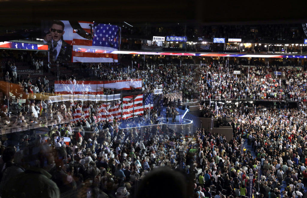 Election 2020 Conventions The stage is reflected on a glass window on the suite level at Wells Fargo Arena as Timmy Kelly sings the national anthem before the start of the second day session of the Democratic National Convention in Philadelphia, in 2016. (John Locher/AP Photo, File)