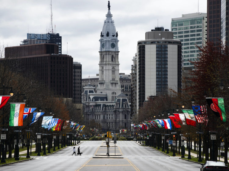 Flags from different countries blow in the wind as City Hall is visible in the background.