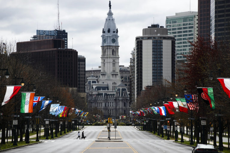 Flags from different countries blow in the wind as City Hall is visible in the background.