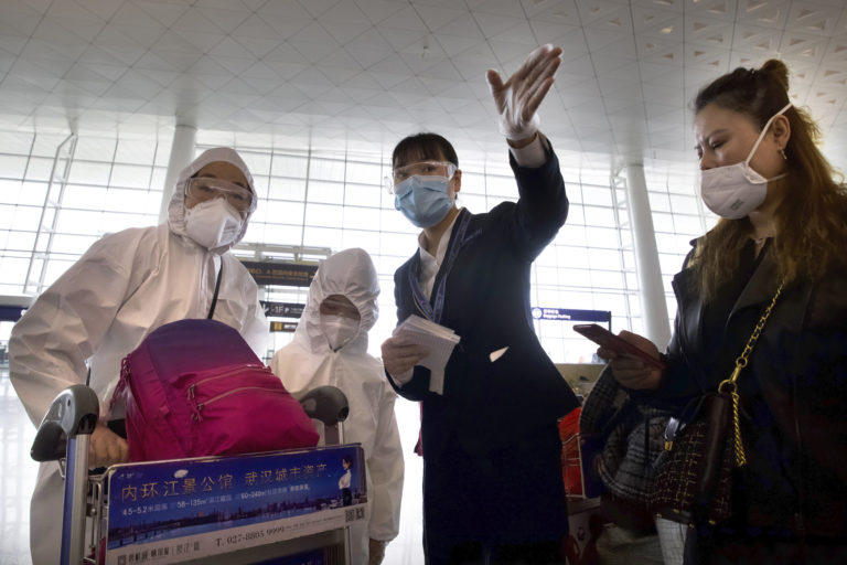A worker directs travelers wearing face masks and suits to protect against the spread of coronavirus at Wuhan Tianhe International Airport in Wuhan in central China’s Hubei Province, Wednesday, April 8, 2020. Within hours of China lifting an 11-week lockdown on the central city of Wuhan early Wednesday, tens of thousands people had left the city by train and plane alone, according to local media reports. (AP Photo/Ng Han Guan)