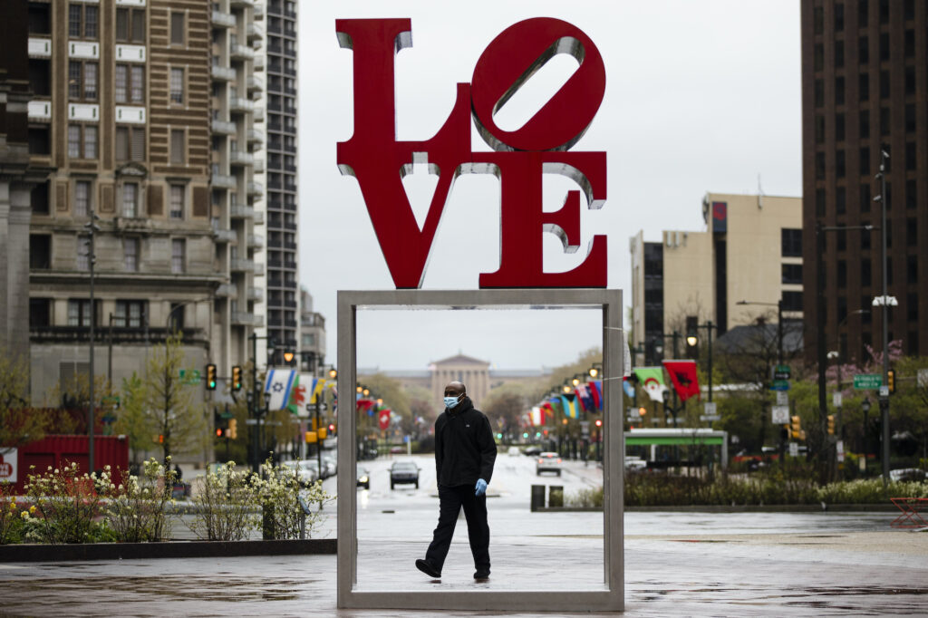 APTOPIX Virus Outbreak Pennsylvania A person wearing a protective face mask and gloves as a precaution against the coronavirus walks through Love Park, in Philadelphia, Monday, April 13, 2020. (Matt Rourke/AP Photo)