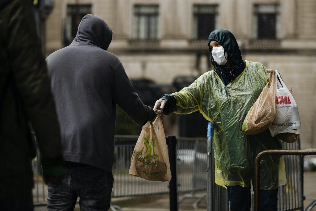 Virus Outbreak Pennsylvania Kris Jaeger with Broad Street Ministry distributes food as part of a new initiative called Step Up to the Plate, during a rainstorm outside of City Hall in Philadelphia, Monday, April 13, 2020. (AP Photo/Matt Rourke)